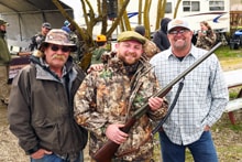 Three hunters — two in camo, one in a blaze orange vest — posing together with a shotgun at the 2024 R3 Upland Bird Hunt