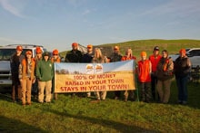 Group of hunters holding a Pheasants Forever banner in warm evening light