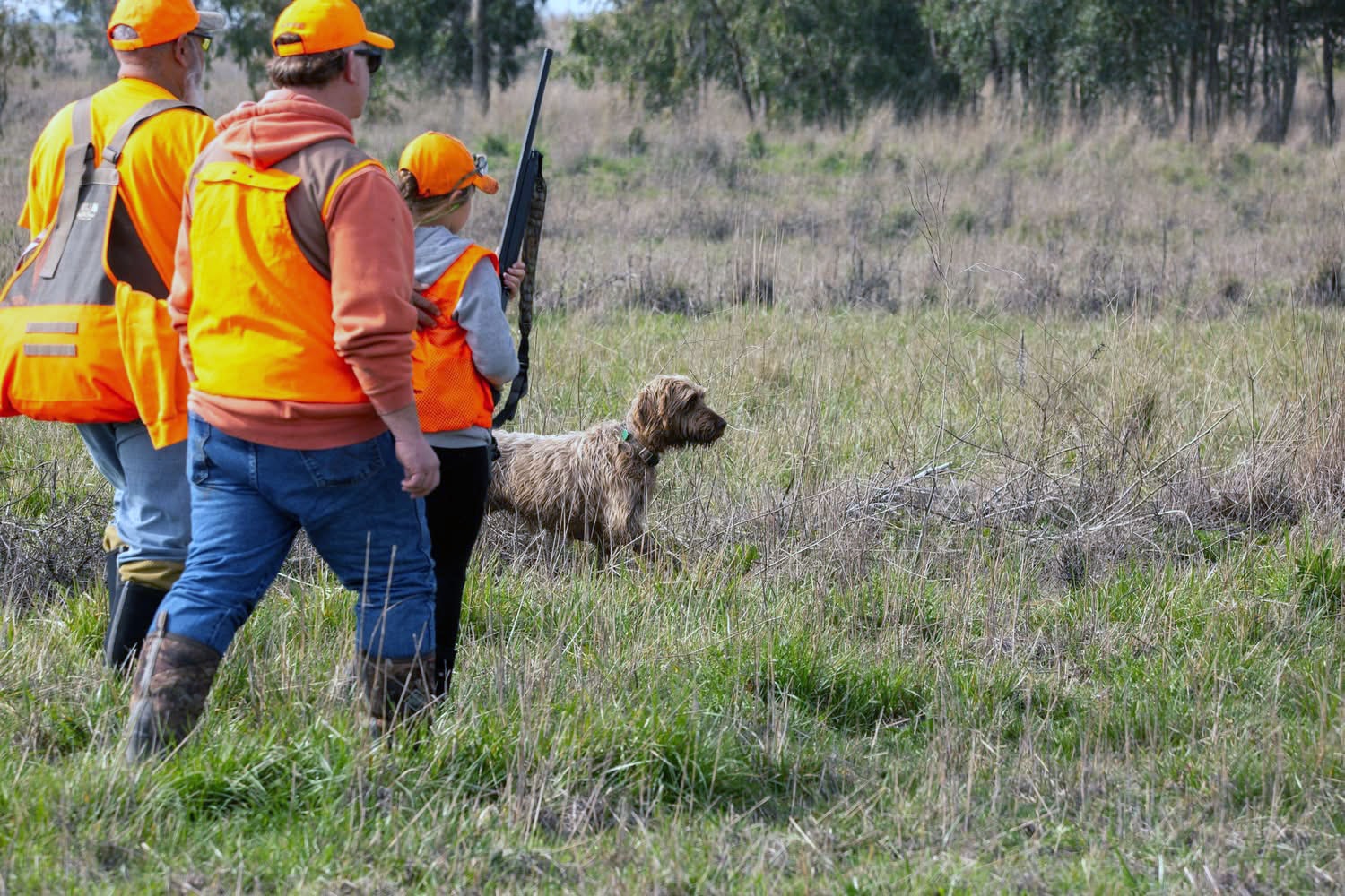 Youth hunter walking through tall grass with a mentor