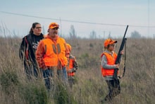 Mentor showing a youth hunter how to handle a shotgun in the field