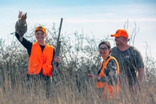Two hunters at the shooting range, one aiming a shotgun