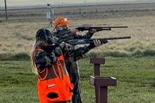 Youth hunter and mentor with a Labrador retriever after a successful hunt